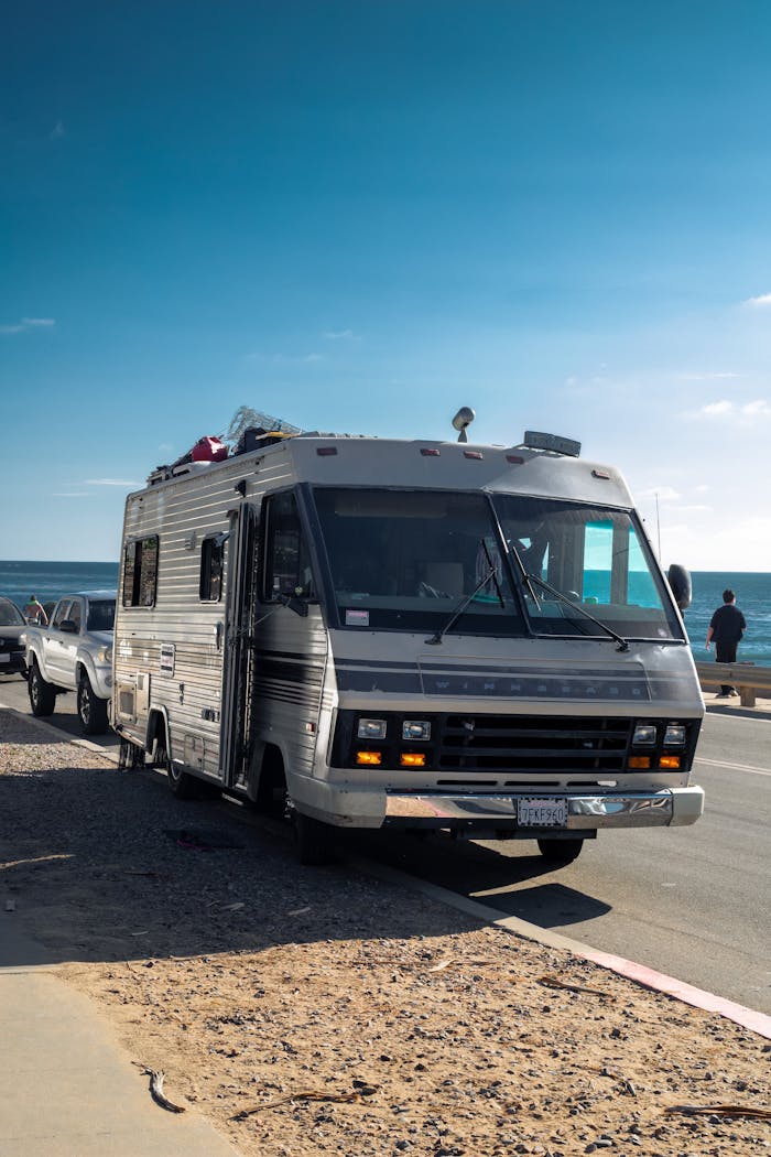 Explore coastal roads with a classic RV under a clear blue sky, perfect for adventurous road trips.